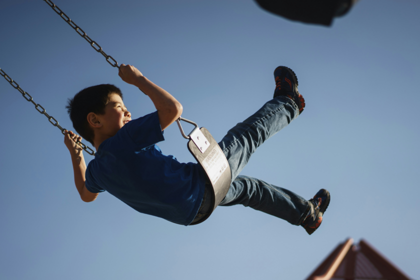Un garçon fait de la balançoire en souriant