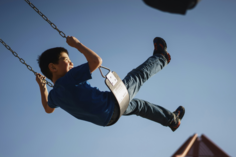 Un garçon fait de la balançoire en souriant